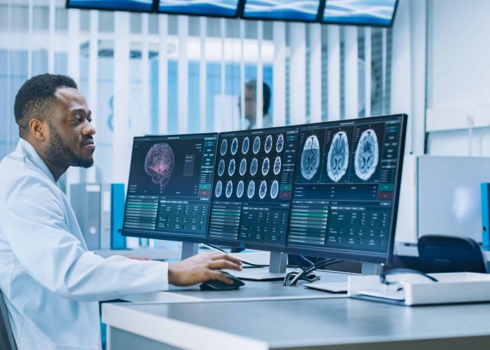 Medical Scientist Working with CT Brain Scan Images on a Personal Computer in Laboratory. Neurologists in Neurological Research Center Working on a Brain Tumor Cure.